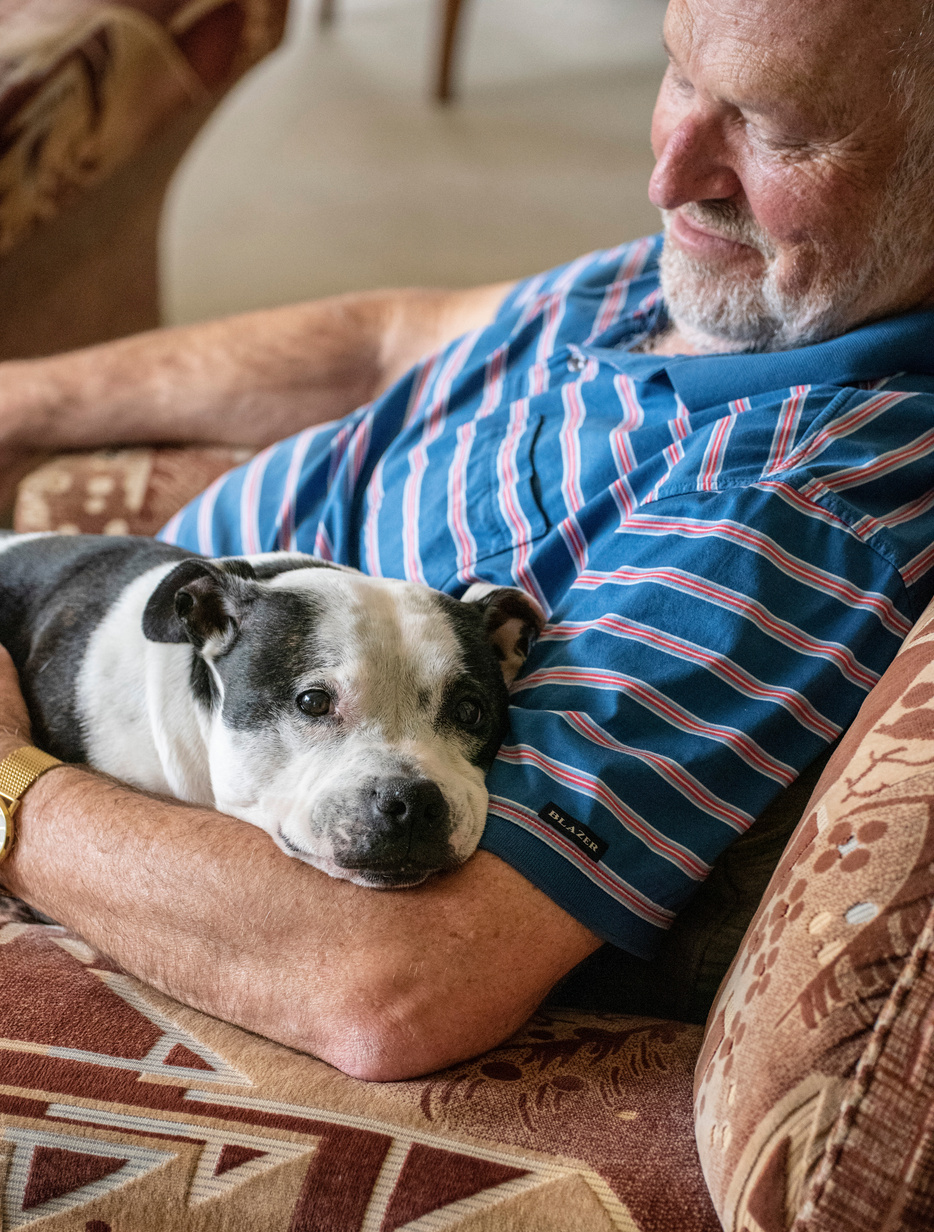 Older man get a cuddle from his dog.
